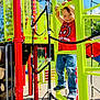 child, playground, climbing, smile, red_shirt, spiderman, yellow_structure, jeans, sneakers, outdoor, daylight, play_equipment, rope_ladder, happy, boy, recreation, summer, fun, park, active