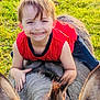 Charleston is registered to the contest to win money with this photo: child, smiling, donkey, animal, outdoor, grass, greenery, sunlight, happy, red_shirt, casual_clothing, playful, nature, young_child, portrait, daylight, farm, pet, cute, fun