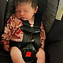 Shayann is registered to the contest to win money with this photo: baby, sleeping, car_seat, child, infant, harness, floral_clothing, peaceful, cute, small_feet, seatbelt, safety, indoors, portrait, resting, newborn, head, face, hands, legs