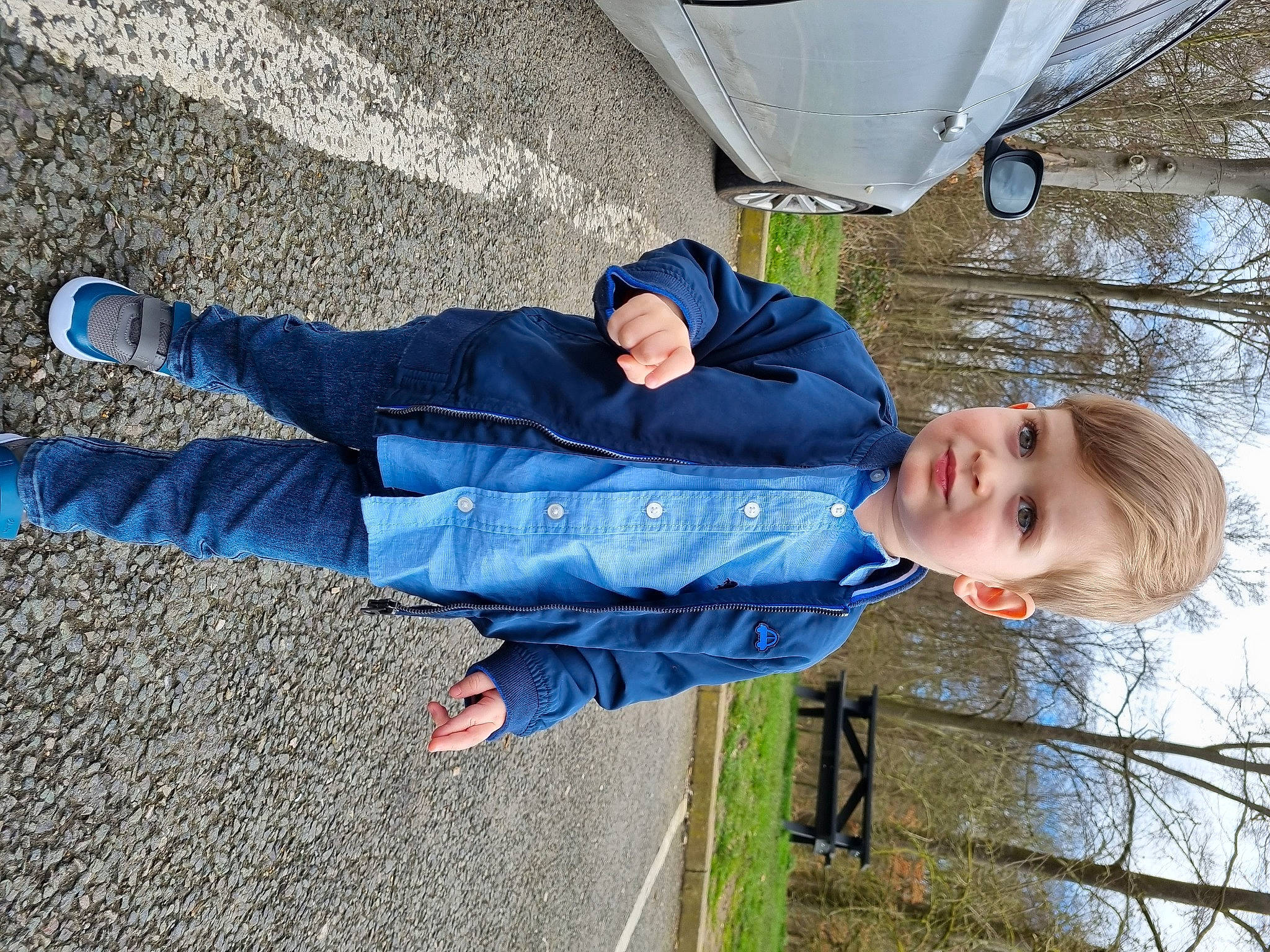Edward is registered to the contest to win money with this photo: asphalt, child, concrete, denim, electric_blue, foot, fun, gesture, grass, human_leg, joy, leisure, people_in_nature, person, road_surface, sitting, sky, smile, toddler, tree