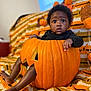 Laiyoni joined the competition — help win amazing prizes! autumn, baby, black_clothing, carved_pumpkin, child, cozy, cute, decorations, face, fall, holiday, indoors, knitted_blanket, legs, orange, portrait, pumpkin, sitting, surprised, window