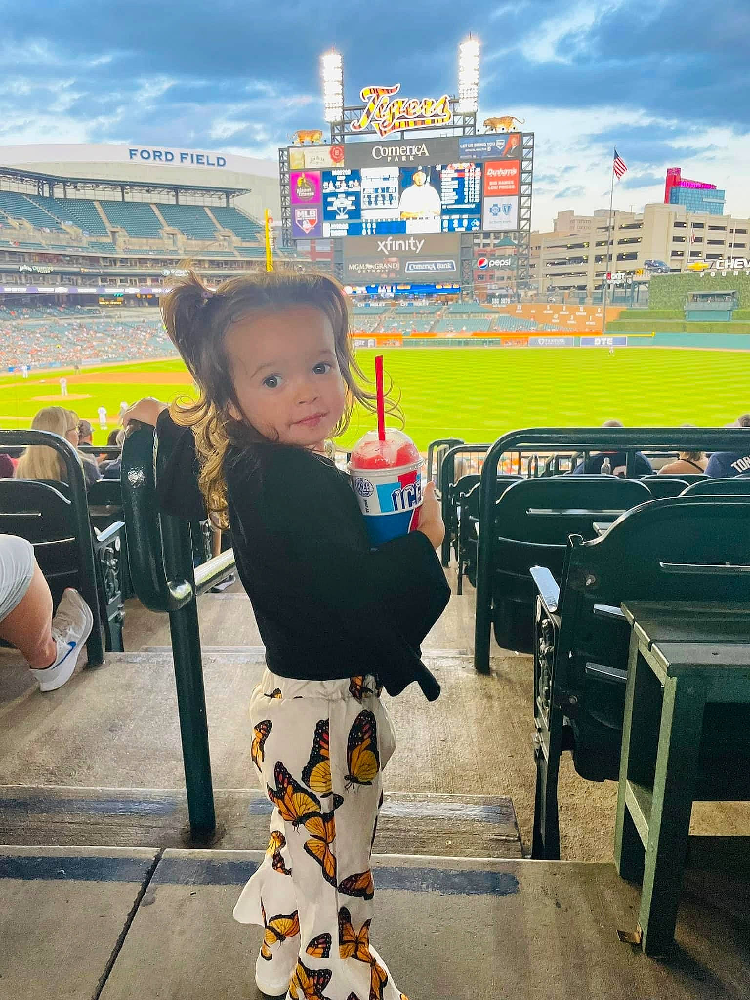 Briella Jade is registered to the contest to win money with this photo: baby, bag, baseball_field, chair, cloud, fan, fun, happy, leisure, luggage_and_bags, person, player, sitting, sky, sport_venue, sports, stadium, t_shirt, team_sport, toddler