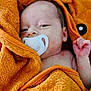 baby, infant, pacifier, orange_towel, wrapped, sleepy, cute, newborn, skin, hand, face, hooded_towel, cozy, child, portrait, resting, indoors, soft_texture, blanket, peaceful