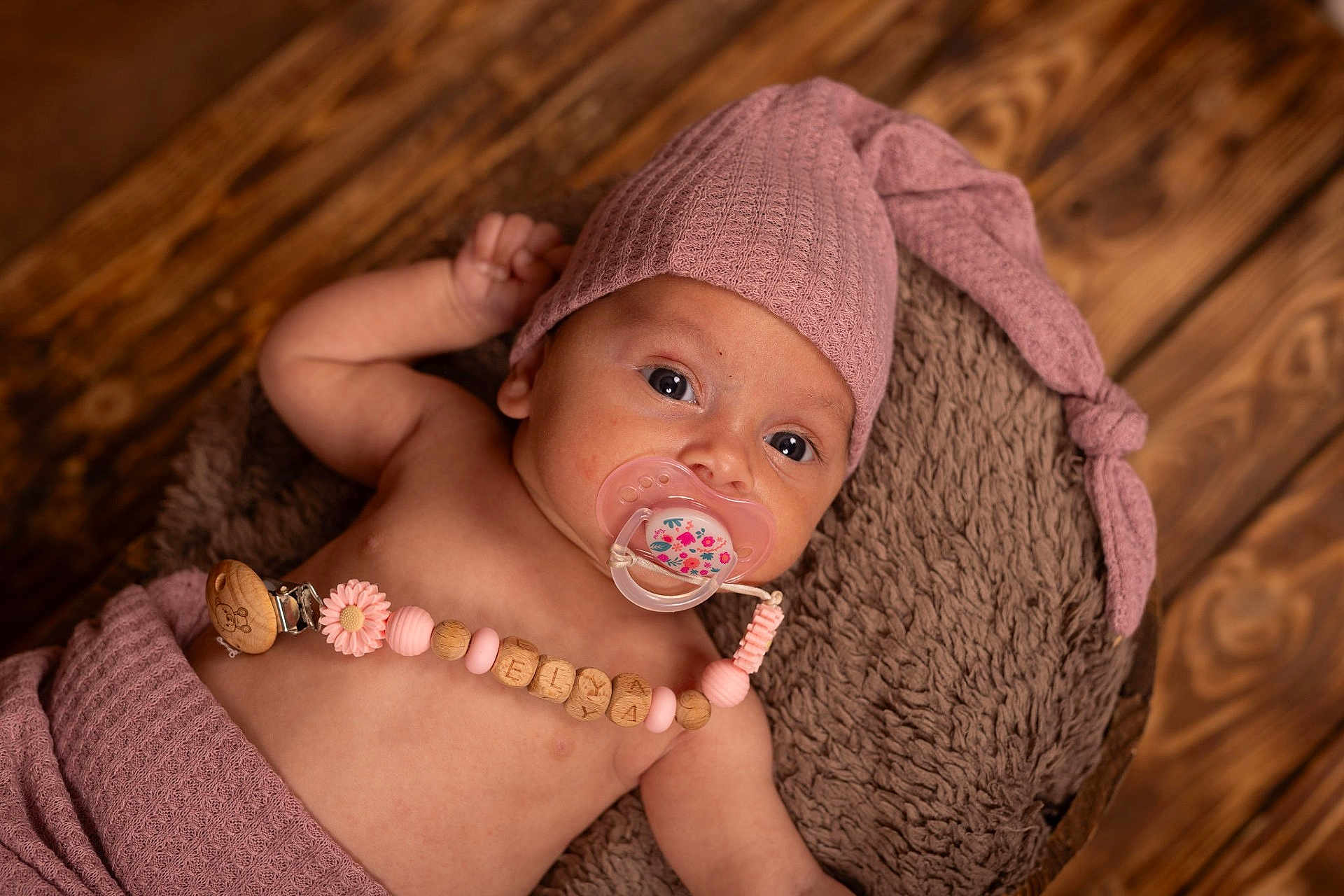Elya participe au concours pour gagner de l'argent avec cette photo : baby, infant, pacifier, hat, wooden_beads, blanket, wrap, face, skin, lying_down, cute, newborn, floor, wood, knitted, clothing, comfort, child, indoors, portrait