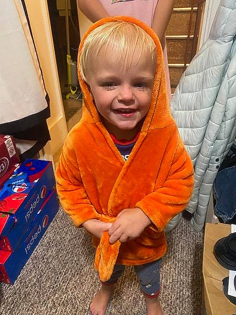 Axle is registered to the contest to win money with this photo: box, carpet, child, floor, flooring, fun, hairstyle, hardwood, head, hoodie, joy, orange, person, play, room, sitting, sleeve, smile, thumb, toddler