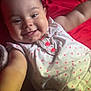 baby, smiling, infant, cute, child, face, arm, clothing, white, pink, hearts, stuffed_animal, toy, red_background, lying_down, portrait, happy, closeup, skin, cheeks