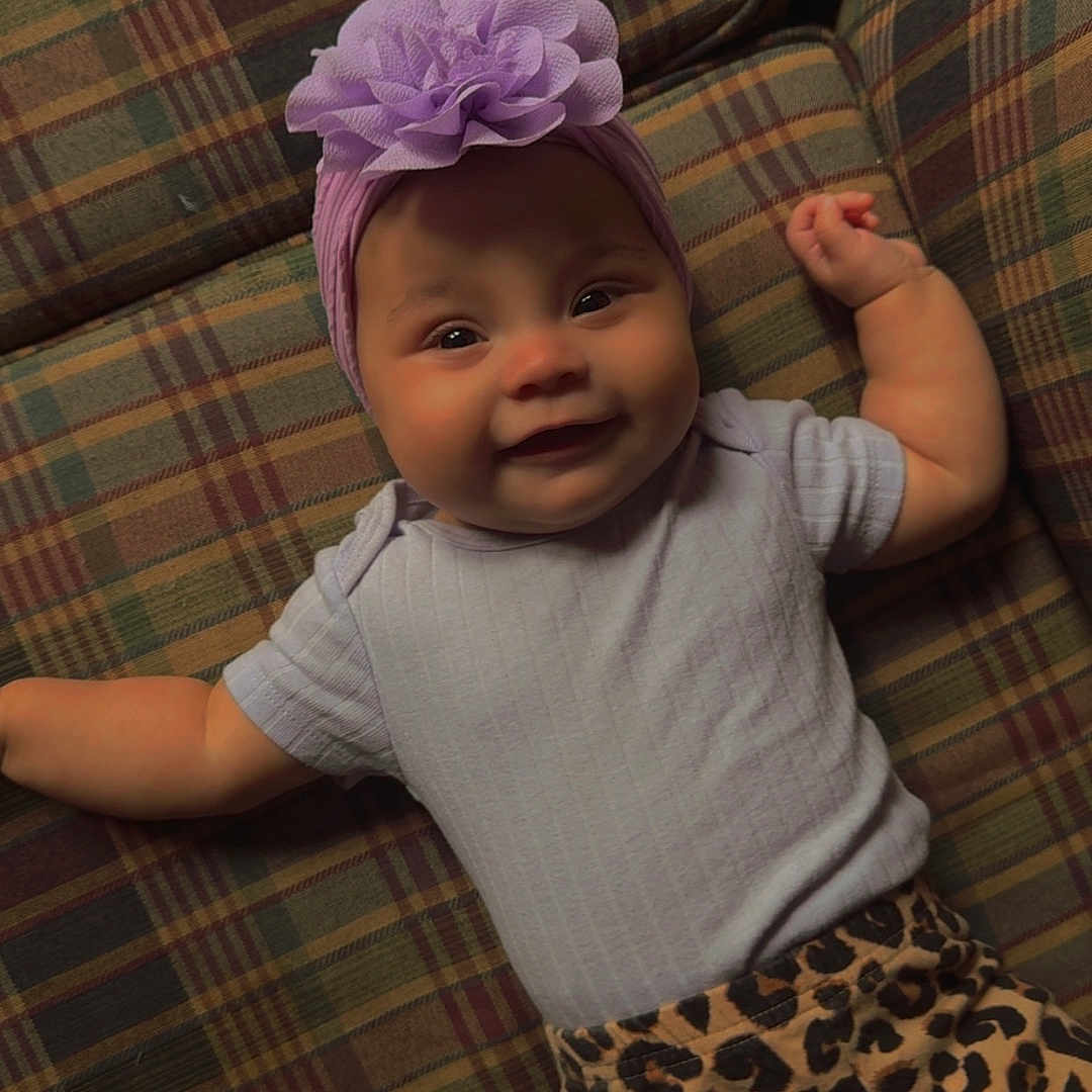 Amayathist joined the competition — help win amazing prizes! baby, child, clothing, cozy, cute, flower_accessory, furniture, happy, headwear, indoors, infant, leopard_print_pants, lying_down, pacifier, patterned, plaid_couch, portrait, purple_headband, smiling, toddler