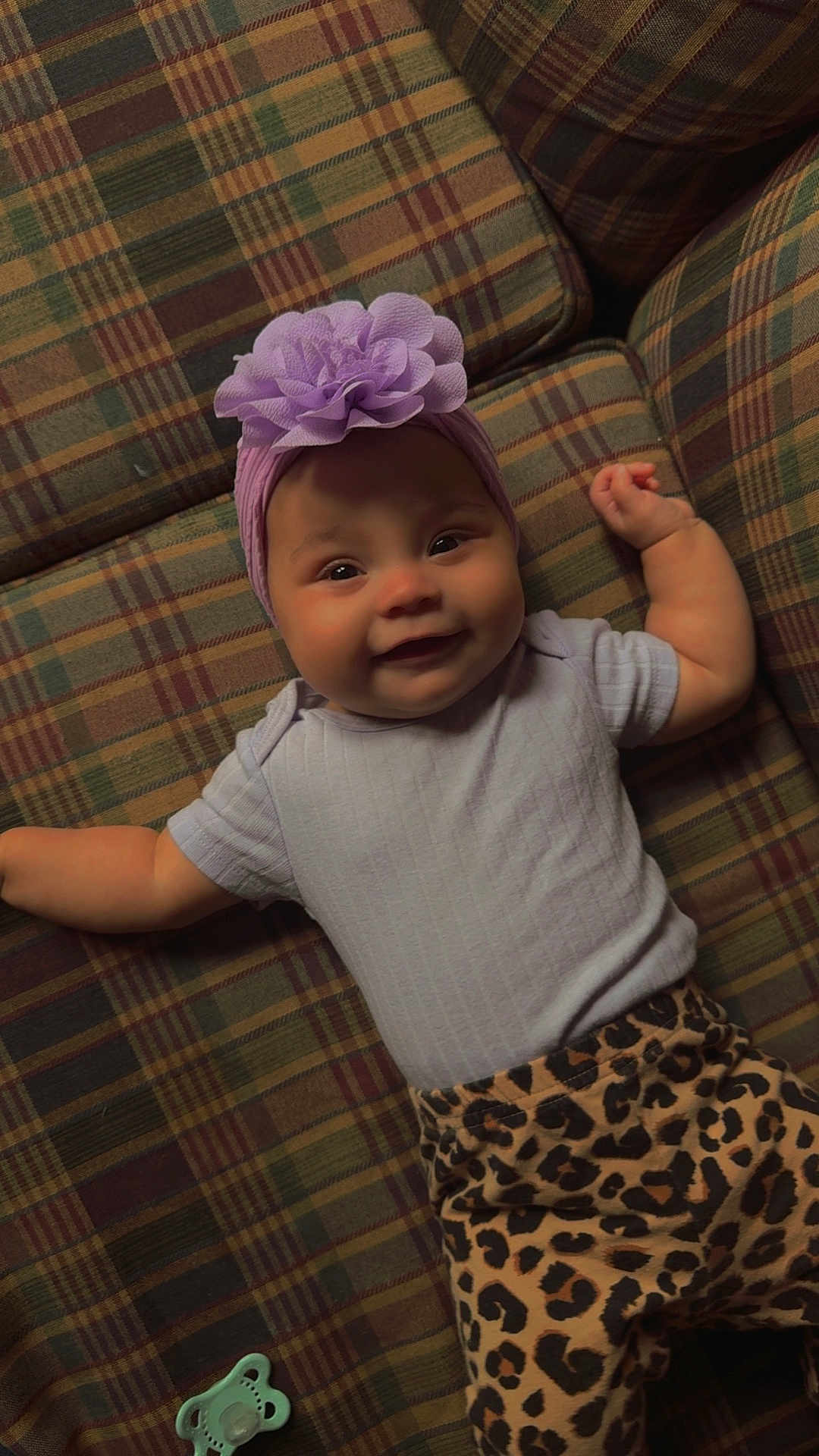 Amayathist joined the competition — help win amazing prizes! baby, smiling, plaid_couch, purple_headband, flower_accessory, leopard_print_pants, infant, happy, cute, lying_down, indoors, pacifier, child, portrait, clothing, headwear, furniture, patterned, cozy, toddler