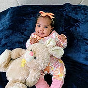 Zenobia is registered to the contest to win money with this photo: baby, blue_background, bow, child, clothing, cozy, cute, feet, happy, headband, indoors, infant, orange, pink, plush_toy, portrait, sitting, smile, soft_toy, teddy_bear