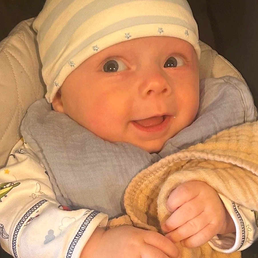 Asher joined the competition — help win amazing prizes! baby, infant, hat, blanket, clothing, hand, face, portrait, cute, smile, child, person, warm, cozy, soft, expression, indoors, newborn, wrapped, comfort