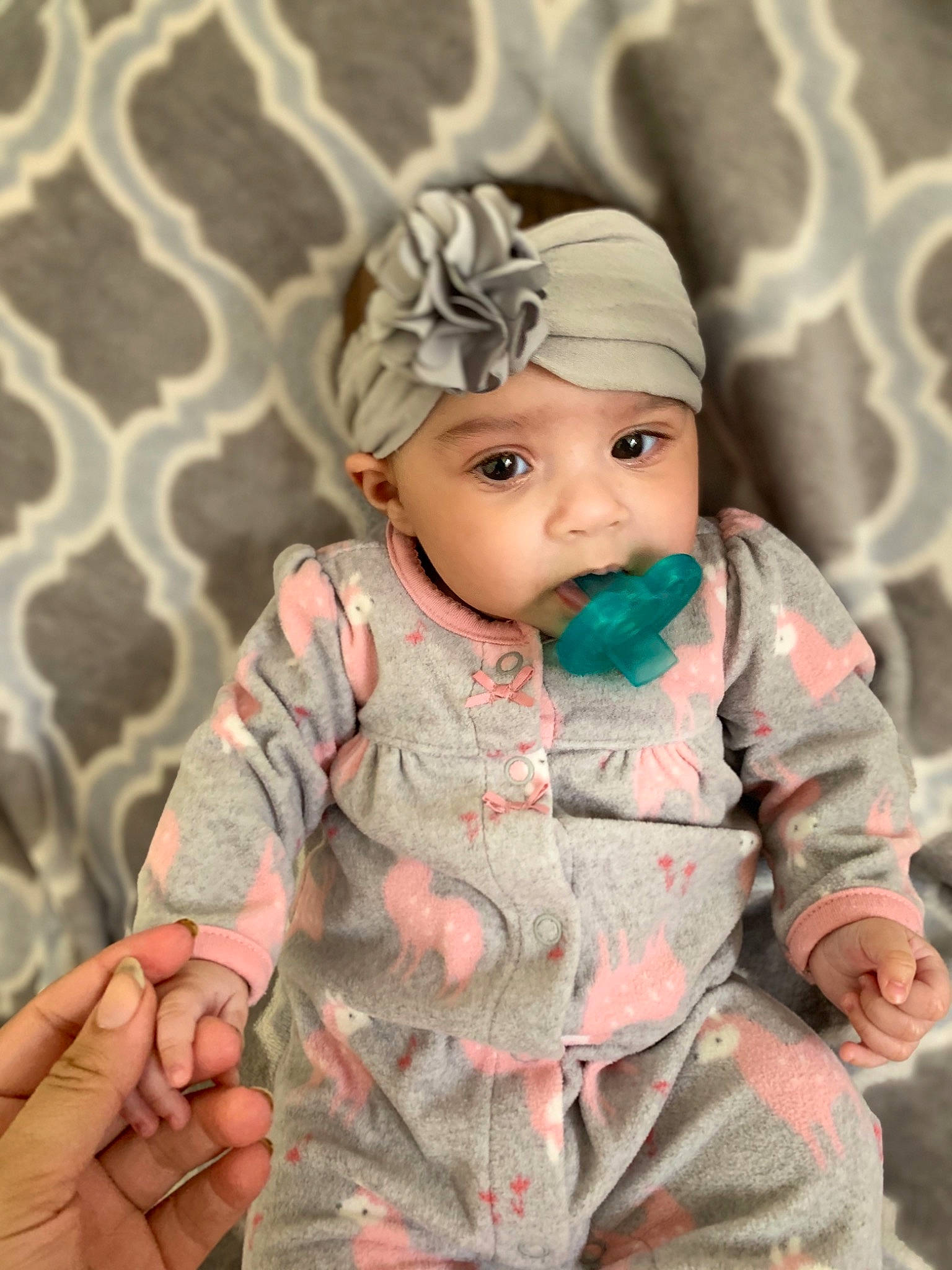 Pandora is registered to the contest to win money with this photo: baby, baby_toddler_clothing, cap, cheek, child, dress, eye, eyelash, face, facial_expression, hand, head, headgear, headwear, iris, lip, pattern, person, pink, skin