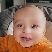 Izak a rejoint le concours — aidez-le/la à gagner de superbes lots ! baby, child, clothing, cute, eyes, face, furniture, hand, happy, high_chair, home, indoor, infant, orange_sweater, person, portrait, skin, smiling, teeth, young