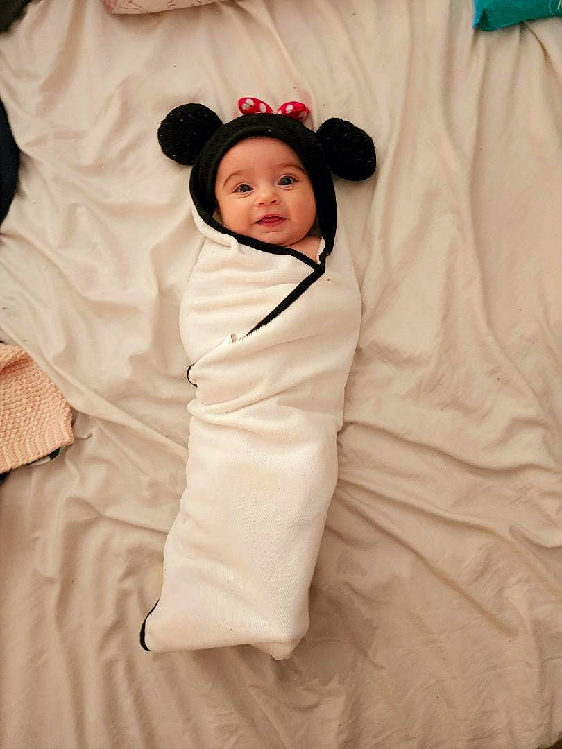 Lilyana is registered to the contest to win money with this photo: baby, baby_products, baby_toddler_clothing, bed_sheet, bedding, child, collar, comfort, fashion_design, fur, happy, hat, headwear, linens, pattern, peach, person, portrait_photography, room, sleeve