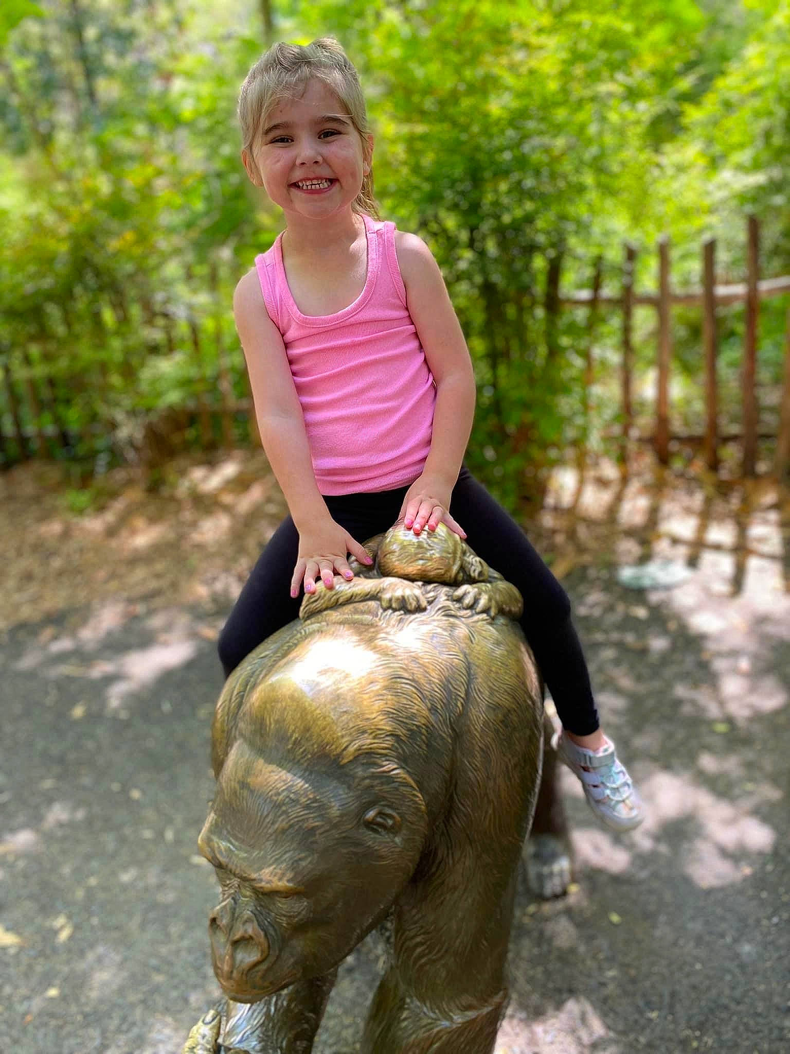 Blakely is registered to the contest to win money with this photo: elephants_and_mammoths, fence, fun, grass, happy, head, joy, leisure, people_in_nature, person, plant, recreation, shorts, smile, soil, statue, t_shirt, terrestrial_animal, toddler, wildlife