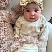 Leya a rejoint le concours — aidez-le/la à gagner de superbes lots ! baby, child, teddy_bear, headband, bow, knitwear, beige, cream, soft, cuddly, portrait, indoor, cute, infant, cozy, plush, face, person, young, seated