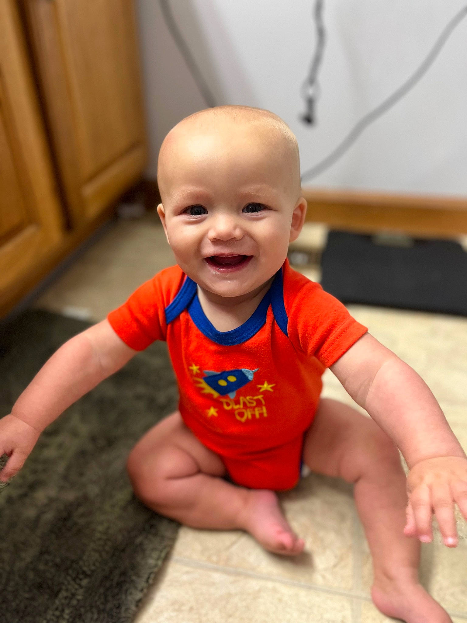 Calvin is registered to the contest to win money with this photo: baby, baby_toddler_clothing, cheek, chin, eye, face, finger, floor, flooring, gesture, happy, head, joy, mouth, nose, person, skin, sleeve, smile, thumb