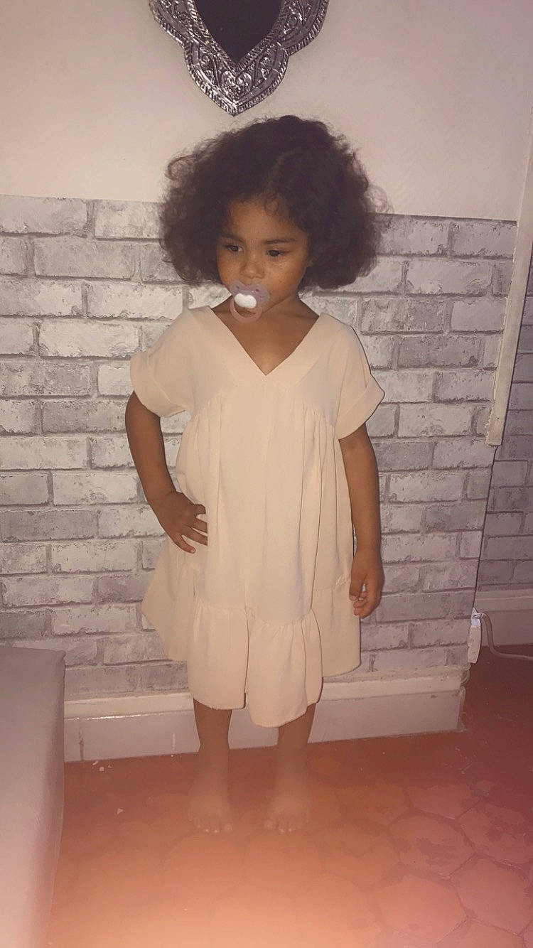 Zayna a rejoint le concours — aidez-le/la à gagner de superbes lots ! baby_toddler_clothing, child, day_dress, dress, face, fashion_design, hair, hairstyle, human_leg, knee, one_piece_garment, pattern, person, room, skin, sleeve, standing, toddler, vintage_clothing, waist