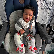 Arya joined the competition — help win amazing prizes! baby, child, smiling, high_chair, curly_hair, clothing, socks, tiger_design, indoor, seat_belt, curtain, pattern, happy, person, infant, cute, playful, home, furniture, seat