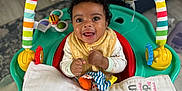 Arya is registered to the contest to win money with this photo: baby, smiling, activity_center, toy, colorful, towel, infant, happy, face, child, indoor, play, seat, curly_hair, blanket, fabric, couch, floor, person, home