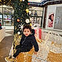 black_jacket, boots, child, christmas_lights, curly_hair, cute, decor, festive, holiday, holiday_decoration, indoor, lights, ornaments, person, seasonal, shopping_mall, sitting, toddler, white_fence, winter_clothing