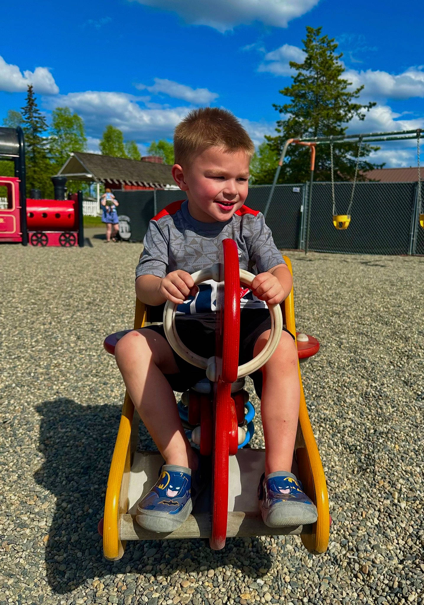 Lucas is registered to the contest to win money with this photo: asphalt, city, cloud, electric_blue, fun, grass, human_leg, kick_scooter, knee, leisure, outdoor_play_equipment, person, recreation, riding_toy, shorts, sky, smile, tire, toddler, tree