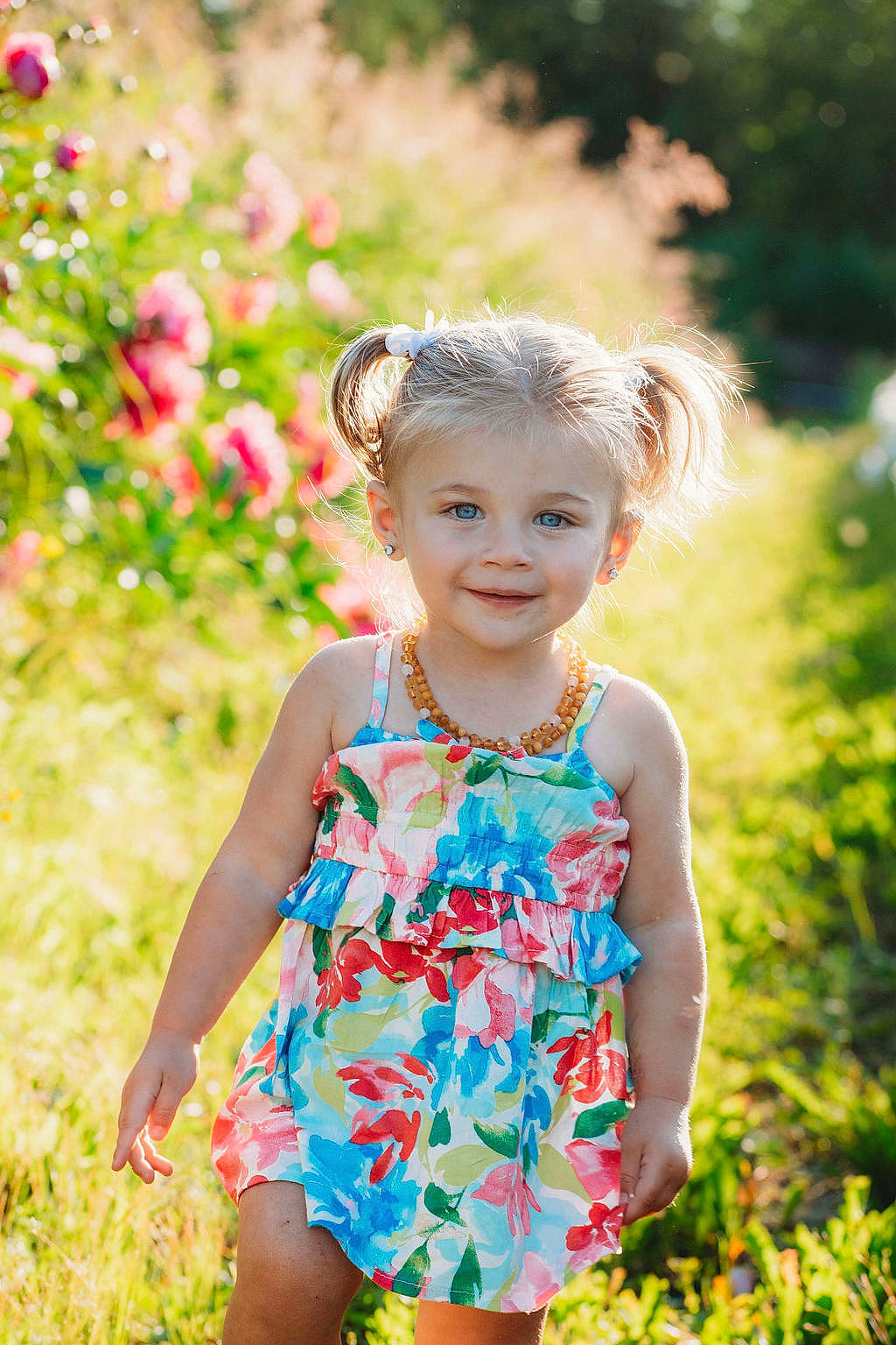 Stella is registered to the contest to win money with this photo: baby_toddler_clothing, botany, dress, eye, face, grass, happy, head, iris, joy, leaf, nature, one_piece_garment, people_in_nature, person, photograph, pink, plant, skin, smile