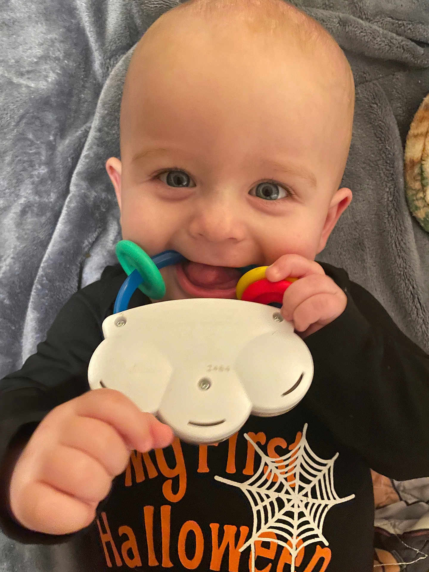 Felix is registered to the contest to win money with this photo: baby, child, face, smile, toy, halloween, black_clothing, blanket, hand, cheerful, infant, cute, indoor, person, closeup, happy, young_child, mouth, holding, cozy