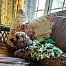 dog, curly_hair, clothing, dress, couch, pillow, lamp, window, indoor, floral_pattern, leather, resting, pet, cozy, home, decor, green, brown, relaxing, furniture