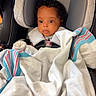 baby, car_seat, blanket, graco, child, infant, face, curly_hair, seatbelt, cozy, indoors, portrait, child_seat, soft_lighting, cute, wrapped, young_child, car_interior, sitting, secure