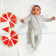 Tashfeen is registered to the contest to win money with this photo: baby, infant, watermelon, fruit, slices, white_sheet, onesie, clothing, laying_down, arms_outstretched, cute, fresh, healthy_food, summer, food_arrangement, child, happy, soft_lighting, playful, portrait