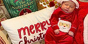 Riley joined the competition — help win amazing prizes! baby, sleeping, christmas, holiday, red_clothing, santa_hat, blanket, pillow, book, the_nutcracker, festive, cozy, indoor, cute, infant, holiday_decor, patterned_fabric, smiling_santa, child, relaxing