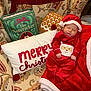 baby, sleeping, christmas, holiday, red_clothing, santa_hat, blanket, pillow, book, the_nutcracker, festive, cozy, indoor, cute, infant, holiday_decor, patterned_fabric, smiling_santa, child, relaxing
