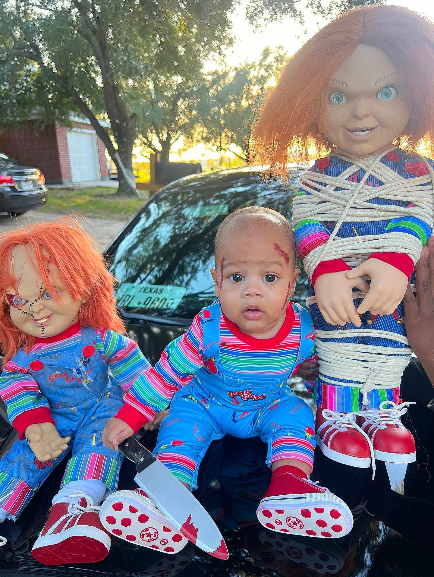 Dshawn joined the competition — help win amazing prizes! baby, child, doll, chucky, costume, halloween, toy, knife, fake_blood, outdoor, car, red_hair, blue_overalls, stripes, face_paint, scary, tied_up, hand, shoes, person