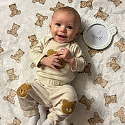 Elohim is registered to the contest to win money with this photo: age_marker, baby, bear_patch, blanket, child, clothing, cozy, cute, frame, happy, indoors, infant, lying_down, playful, portrait, smiling, soft_texture, teddy_bear_pattern, white_socks, young_child