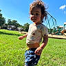 child, toddler, grass, playground, outdoor, sunny, blue_sky, shorts, shirt, grass_blade, play_equipment, tree, house, daylight, person, young_child, casual_clothing, summer, fun, nature