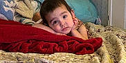 Viviana is registered to the contest to win money with this photo: bed, blanket, child, clothing, comfort, cozy, curious, expression, face, home, indoor, lying_down, person, pillow, portrait, resting, room, sleep_area, toddler, young_child