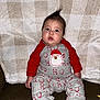 baby, blanket, checkered_pattern, child, couch, cute, expression, fabric, face, foot, hair_tuft, hand, holiday_theme, indoors, infant, pajamas, person, red_sleeves, santa_claus, sitting