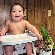 Bobbie joined the competition — help win amazing prizes! baby, bare_torso, child, cup, drooling, feeding_tray, hat, highchair, hot_dog_buns, hot_sauce_bottle, indoor, plant, plate, potted_plant, shelf, smile, tinsel, toes, wood_paneling, wooden_table