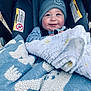 adorable, baby, beanie, blanket, blue_blanket, bundled, car_seat, chubby_cheeks, cozy, fabric, face, harness, infant, outdoors, pattern, portrait, smile, stroller, teether, warning_label