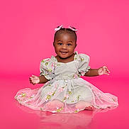 Cecelia joined the competition — help win amazing prizes! baby, child, girl, smiling, happy, dress, pink_background, bows, sitting, portrait, cute, studio, fashion, flower_pattern, infant, young_child, adorable, pretty, innocent, childhood