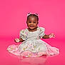 baby, child, girl, smiling, happy, dress, pink_background, bows, sitting, portrait, cute, studio, fashion, flower_pattern, infant, young_child, adorable, pretty, innocent, childhood
