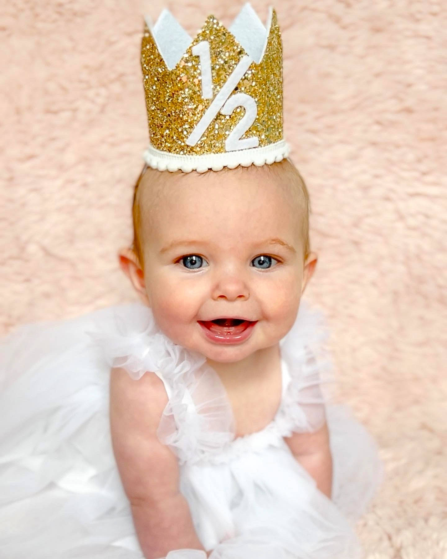 Gracelynne is registered to the contest to win money with this photo: baby_toddler_clothing, bridal_accessory, costume_hat, crown, dress, eye, face, hand, happy, hat, head, headband, headgear, headpiece, jewellery, joy, party_hat, person, pink, smile