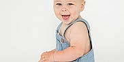 Marshall is registered to the contest to win money with this photo: baby, child, smiling, denim, romper, sitting, happy, cute, infant, portrait, studio, light_background, skin, face, blue_eyes, short_hair, one_person, isolated, playful, young