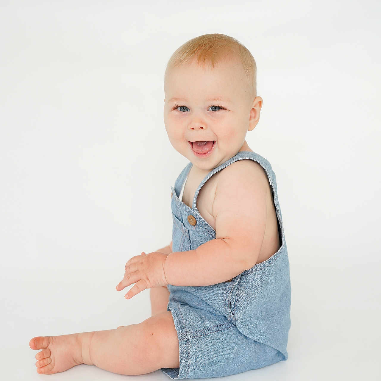Marshall is registered to the contest to win money with this photo: baby, blue_eyes, child, cute, denim, face, happy, infant, isolated, light_background, one_person, playful, portrait, romper, short_hair, sitting, skin, smiling, studio, young