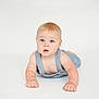 baby, child, denim_overalls, blue_eyes, blonde_hair, infant, cute, crawling, white_background, soft_lighting, expression, portrait, skin, young_child, studio_photo, hands, face, curious, minimalistic, innocent