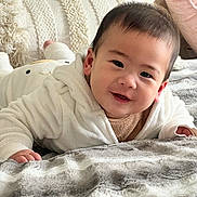 Keegan is registered to the contest to win money with this photo: baby, child, smiling, face, blanket, pillow, bedroom, cozy, indoor, white_clothing, soft_texture, cute, infant, portrait, happy, young_child, lying_down, home, toddler, person