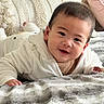 baby, child, smiling, face, blanket, pillow, bedroom, cozy, indoor, white_clothing, soft_texture, cute, infant, portrait, happy, young_child, lying_down, home, toddler, person