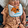 Mayron a rejoint le concours — aidez-le/la à gagner de superbes lots ! baby, smiling, infant, bib, clothing, peach_outfit, bedspread, cartoon, cute, happy, child, person, fabric, pattern, shorts, sitting, skin, head, hand, foot