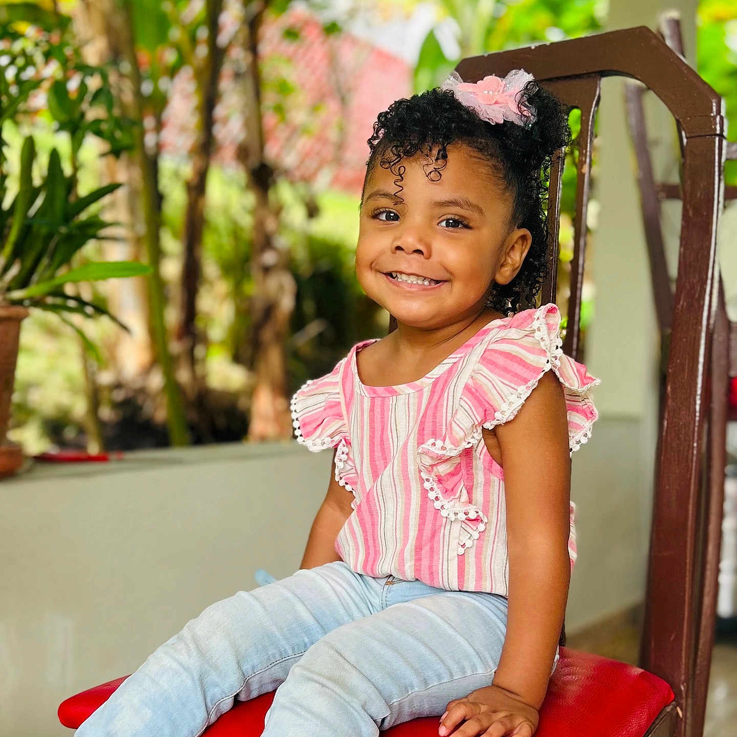 Lelani is registered to the contest to win money with this photo: blackhair, child, clothing, curlyhair, dimples, face, female, furniture, girl, hair, happy, head, henna, jeans, pants, person, plant, sitting, sleeve, smile