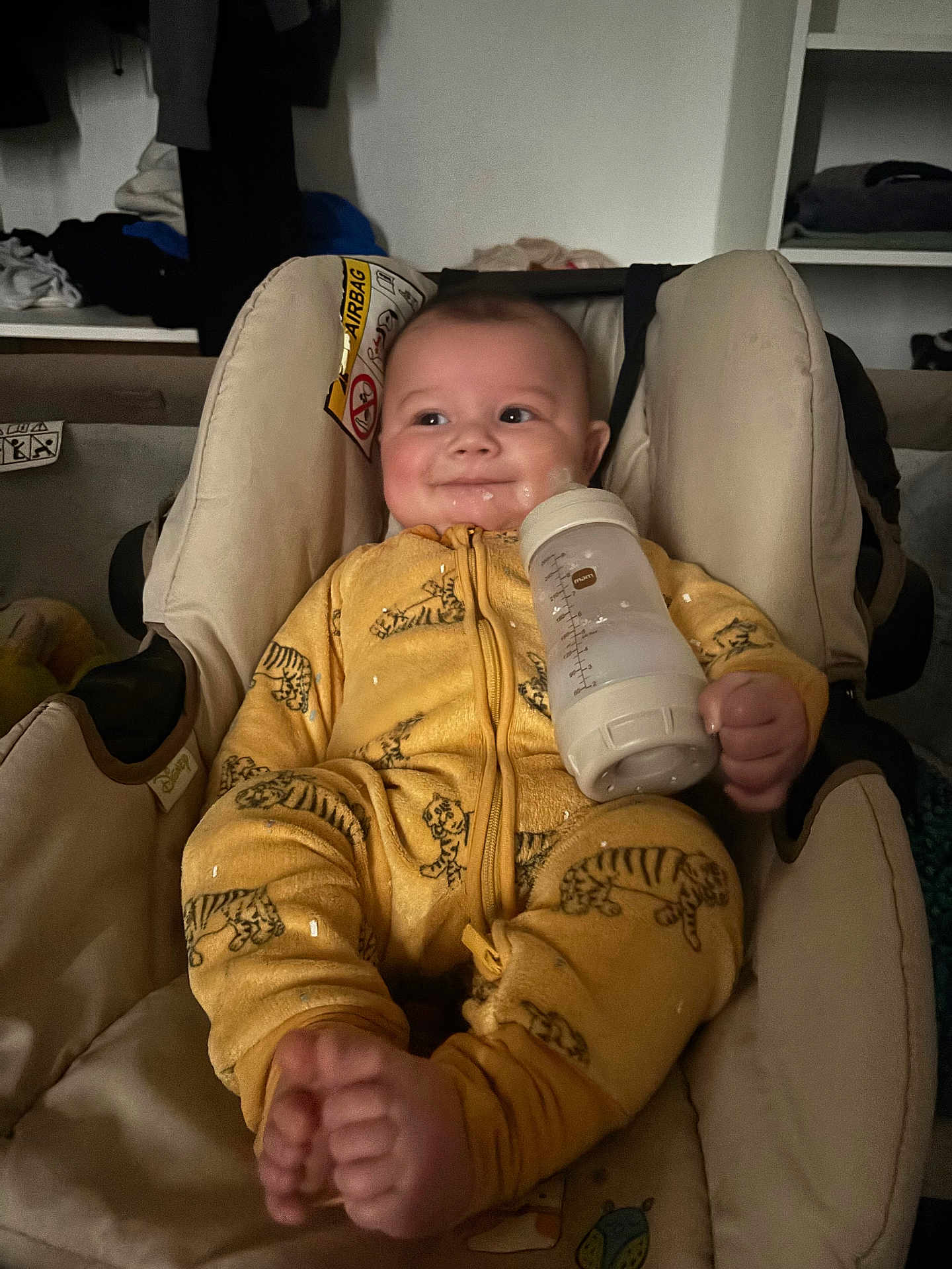Khelid a rejoint le concours — aidez-le/la à gagner de superbes lots ! baby, infant, car_seat, bottle, milk, yellow_onesie, tiger_print, smile, feet, hands, face, cheeks, seat_padding, warning_label, clothing, indoor, soft_lighting, portrait, cute, cozy